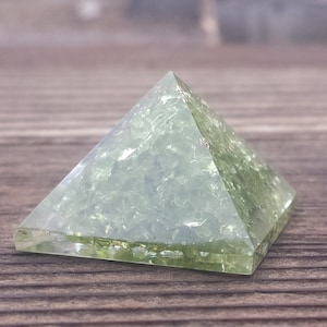 Könnte beinhalten: Eine grüne Kristallpyramide mit einer funkelnden, strukturierten Oberfläche.