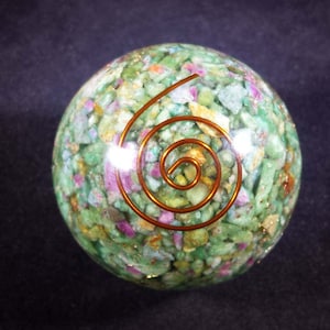 Peut inclure: Une sphère de cristal verte, rose et dorée avec un motif en spirale de fil de cuivre.