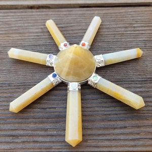 May include: A yellow crystal pyramid with seven yellow crystal points radiating outward. The points are arranged in a star shape. Each point has a small, colorful gemstone at the end.