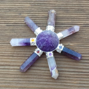 May include: Amethyst crystal chakra balancing wheel with seven chakra stones. The wheel is made of polished amethyst and has a round shape. The chakra stones are arranged in a circle around the wheel and are each a different color.