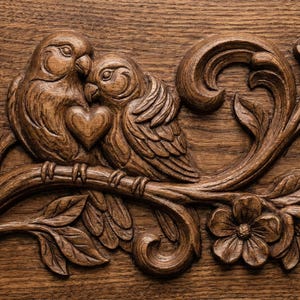 May include: A carved wooden relief featuring two birds nestled together on a branch, with a heart shape between them. The birds and floral elements are intricately detailed in a warm brown tone, creating a rustic and romantic aesthetic.