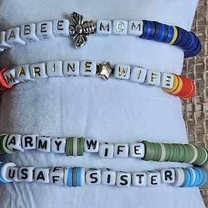 May include: Four bracelets with white letter beads spelling out "BEE MOM", "MARINE WIFE", "ARMY WIFE", and "USAF SISTER". Each bracelet has colorful beads between the letter beads.