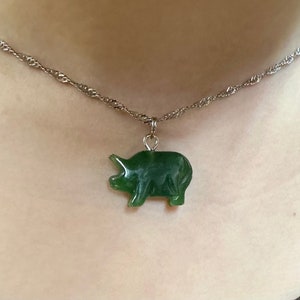 May include: A silver chain necklace with a green jade pig pendant.
