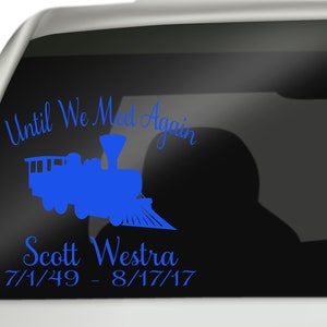 May include: A blue train silhouette with the text "Until We Meet Again" above it and "Scott Westra 7/1/49 - 8/17/17" below it. This is a memorial sticker for a car window.