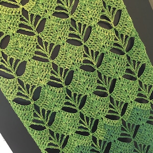 Può includere: Una sciarpa all'uncinetto verde e gialla con un motivo a foglie.