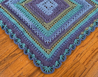 May include: A crocheted blanket with a scalloped edge in shades of blue, green, and purple.