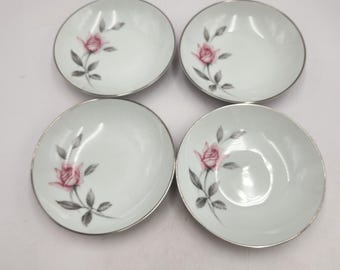 May include: Set of four white porcelain bowls with a silver rim. Each bowl features a pink rose with green leaves.