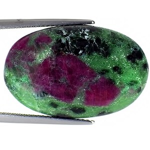 May include: Oval-shaped green and pink gemstone with black flecks. The gemstone is set in a silver setting.