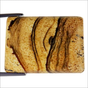 Puede incluir: Una piedra preciosa de ágata rectangular, con bandas marrones claras y oscuras, con una superficie lisa y pulida. La piedra tiene un patrón de bandas marrones claras y oscuras en espiral.