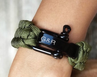 Puede incluir: Tres pulseras de paracord con cierres de metal negro. Las pulseras son de color azul, verde y negro.