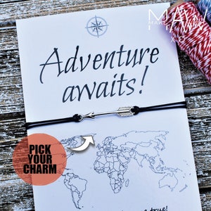 May include: A white card with the words "Adventure awaits!" and a world map graphic. A silver arrow charm bracelet is displayed on the card. The card also has a compass rose graphic and the words "Pick Your Charm".