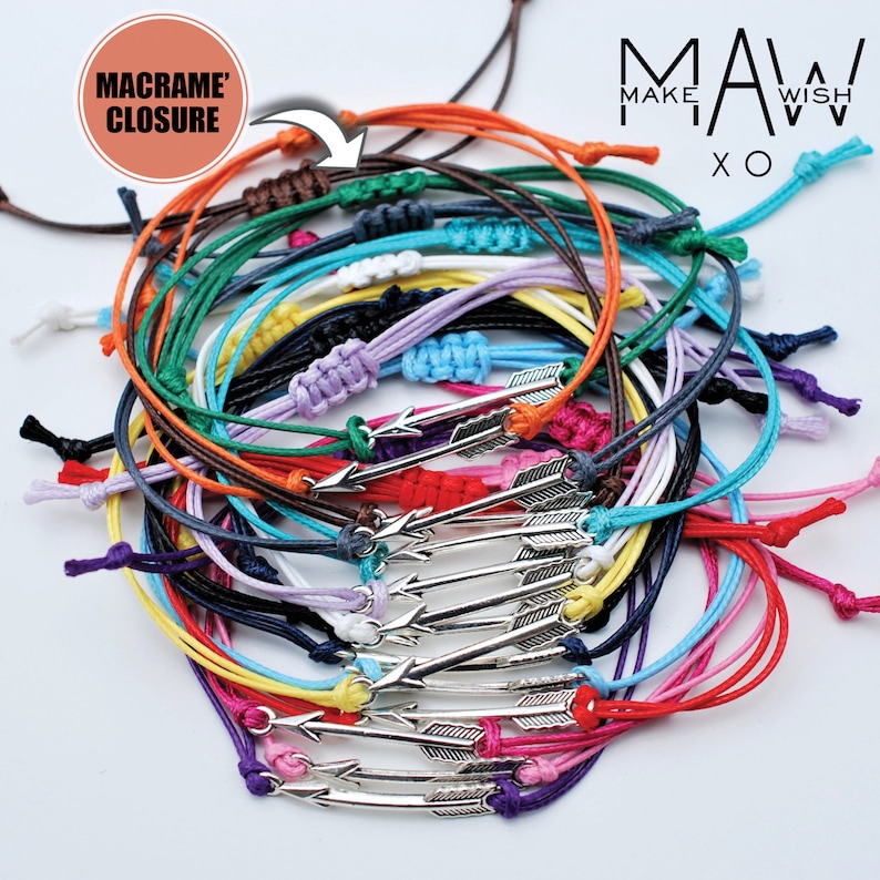 May include: A stack of colorful friendship bracelets with arrow charms. The bracelets are made of thin cord and have a macrame closure. The text "MAKE A WISH" is visible in the background.