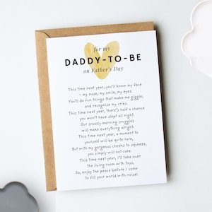 A white folded greeting card laying flat on top of a kraft brown envelope. The design reads "for my daddy-to-be on Father's day" in black modern fonts. A yellow heart design sits behind the title. Our original poem from the baby bump to their soon-to-be parent is below in fun, playful black fonts (for wording, go to our description)