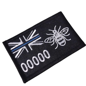 May include: Black rectangular patch with a Union Jack design, a blue stripe, and a white bee illustration. The patch also features the number "00000" in white. This patch is likely an emblem or badge, possibly for uniform or apparel.