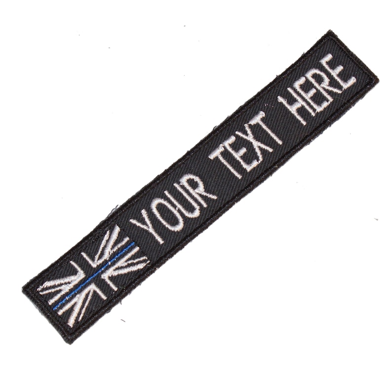 May include: Black fabric patch with a white embroidered Union Jack flag and the text "YOUR TEXT HERE" in white.