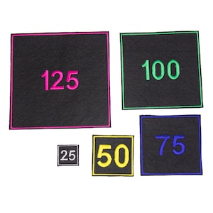 May include: Five black felt squares with different coloured borders and numbers embroidered on them. The numbers are 25, 50, 75, 100, and 125.
