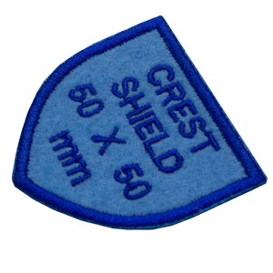 May include: Blue felt shield patch with white embroidery that reads "Crest Shield 50 x 50 mm".