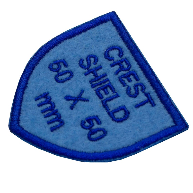May include: Blue felt shield patch with white embroidery that reads "Crest Shield 50 x 50 mm".