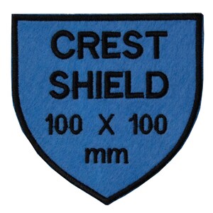 May include: Blue felt shield patch with black embroidered text that reads "CREST SHIELD 100 x 100 mm".