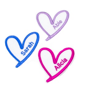 May include: Three heart-shaped patches with different coloured outlines and names embroidered inside. The names are "Able", "Sarah", and "Alicia".