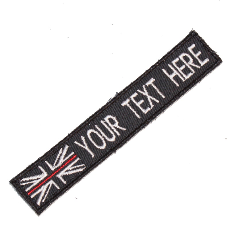 May include: Black fabric patch with a white embroidered Union Jack flag and the text "YOUR TEXT HERE" in white.