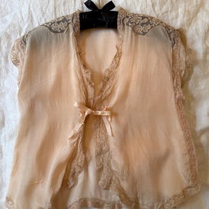 Chaqueta de cama de seda de los años 20 con ribete de encaje y lazo.