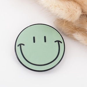 Könnte beinhalten: Ein grüner Smiley-Telefon-Griff mit schwarzem Umriss.