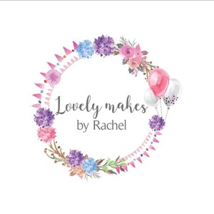 May include: Watercolor logo design featuring a floral wreath with pink, purple, and blue flowers. The text "Lovely makes by Rachel" is written in a script font, with pink and white balloons on the right side.