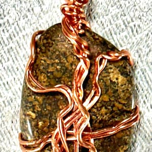 May include: A copper wire wrapped pendant featuring a brown and gold speckled stone.