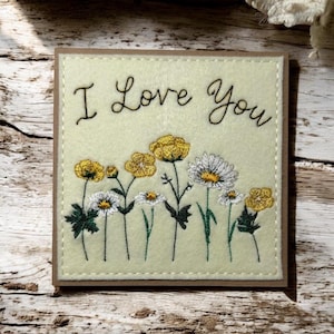 Belle carte de voeux faite main. Broderie, « Je t'aime » avec des marguerites et des renoncules. Carte d'anniversaire ou d'anniversaire parfaite.