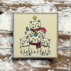 a* Une carte de voeux de fête de Noël avec chat brodée à la main. Broderie. « Chœur de Noël »