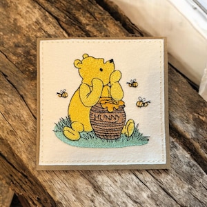 Preciosa tarjeta de felicitación hecha a mano con bordado de estilo vintage. El oso Winnie Pooh contempla su gran tarro de miel. Perfecta para enmarcar.