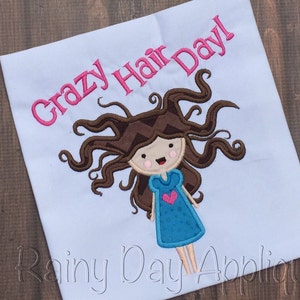 May include: Embroidered design on a white fabric featuring a cartoon girl with brown hair and a blue dress. The text "Crazy Hair Day!" is embroidered in pink above the girl.