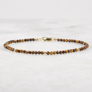 May include: A delicate gold chain bracelet with small, faceted tiger's eye beads.