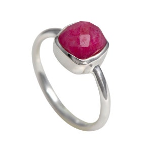 May include: A silver ring with a square-shaped, faceted, pink gemstone.