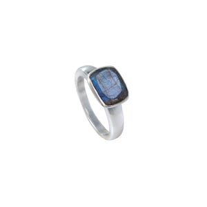 Puede incluir: Un anillo de plata con una piedra preciosa cuadrada de color azul y negro.