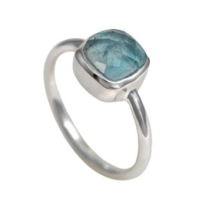 May include: A silver ring featuring a light blue gemstone. The gemstone is square-shaped with rounded edges.