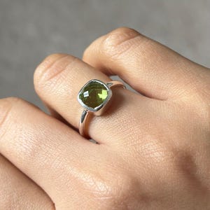 Peut inclure: Une bague en argent avec une pierre précieuse verte carrée.