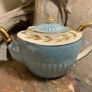 Tetera de cerámica Gibsons #W607 de los años 50 con hojas de laurel doradas y loza azul lustrosa. Tetera de forma georgiana con lados festoneados. Decoración vintage de estilo campestre. Inglaterra.