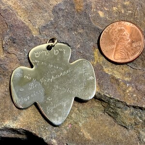 Op de afbeelding: Gouden Girl Scout-speld in de vorm van een klavertjevier met de woorden "Be Prepared" erop. De speld heeft ook de woorden "Sois Prete", "We Es Bereid", "&Eacute;gy R&eacute;gen", "Будь готов", "Van Bereidt" en "Be Prepared" erop.
