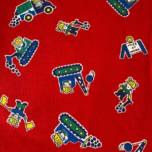 May include: Red fabric with a repeating pattern of mice operating construction equipment. The mice are wearing hard hats and driving bulldozers, excavators, and cranes. A sign reads "Mice at Work".