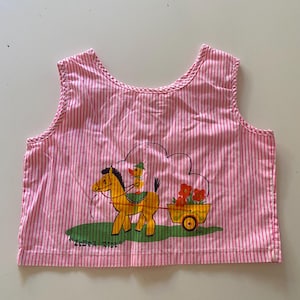 May include: Pink and white striped sleeveless top with a cartoon horse pulling a yellow cart filled with red flowers. A duck is riding on the horse. The text "ZEBRA RIDE" is printed on the bottom.