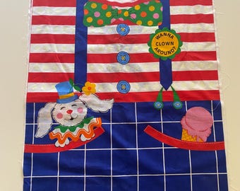 May include: A colorful clown costume panel with a red and white striped top, blue suspenders, and a blue checkered bottom. Features a cartoon bunny, a green polka-dot bow tie, and the text "Wanna Clown Around?"