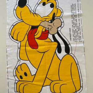 May include: A Pluto character fabric panel with a yellow body, black ears, and a red tongue. The panel includes instructions for assembling the plush toy, with text that reads "Leave Open for Stuffing."