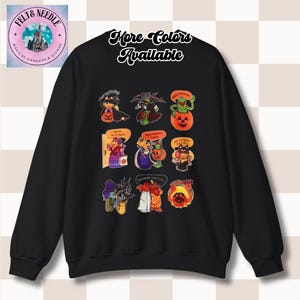 May include: Black sweatshirt featuring Halloween-themed cartoon characters. The design includes witches, pumpkins, and other spooky figures with text bubbles. The words "More Colors Available" are written in cursive.