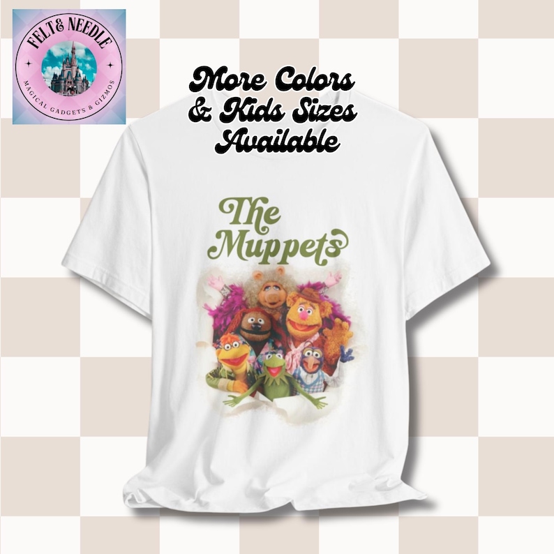 May include: White t-shirt with a green and white graphic of the Muppets characters. The text "The Muppets" is above the image. The text "More Colors & Kids Sizes Available" is above the image.