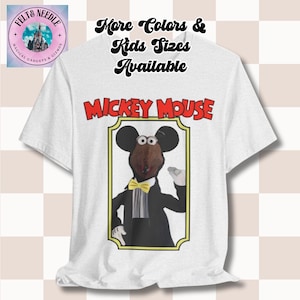 May include: White t-shirt featuring a cartoon image of Mickey Mouse in a tuxedo with a yellow bow tie. The text "MICKEY MOUSE" is above the image in red letters. The shirt also has the text "More Colors & Kids Sizes Available".