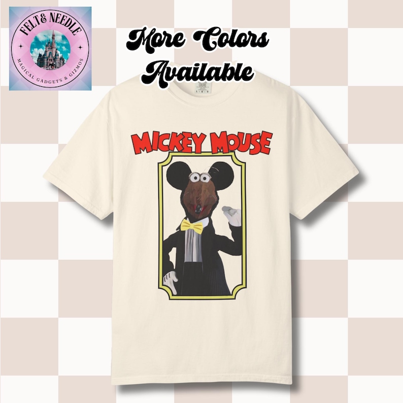 May include: A cream-colored short-sleeve t-shirt featuring a graphic of a puppet-style Mickey Mouse character in a black tuxedo with a yellow bow tie, framed in a gold border. The text MICKEY MOUSE appears in red above the frame.