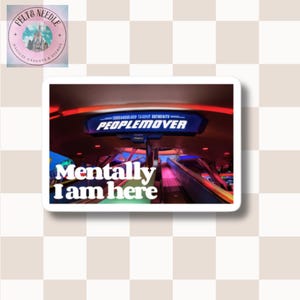 Könnte beinhalten: Ein weißer Aufkleber mit einem Foto einer futuristisch aussehenden Fahrt mit dem Text "Tomorrowland Transit Authority Peoplemover" und dem Text "Mentally I am here" in weißen Buchstaben.