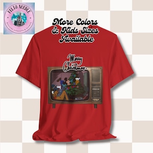 May include: Red t-shirt with a vintage television screen graphic featuring Mickey Mouse and Pluto celebrating Christmas. The text "Merry Christmas" is above the television and the text "More Colors & Kids Sizes Available" is above the television.